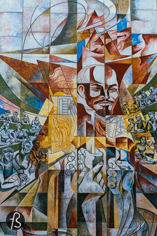 This Lenin mural in Halle Neustadt was unveiled in 1971 by Erich Enge, a bricklayer by training who found himself in large format paintings. His mural is named %22He stirred the sleep of the world%22 and visually presents the three essential reforms that Lenin initiated in the Soviet Union. First, with the elimination of illiteracy, followed by a country comprehensive land reform and the country's electrification in the 1920s. All these elements are presented around Lenin's face in the mural, surrounded by young people reading and learning.