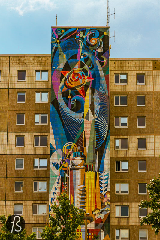 Another mural by the same artist is called %22The man-controlled forces of nature and technology%22 on its left side. At the bottom of this massive socialist mural, you can see workers and miners powering an explosion of industrial force that culminates with the development of technology and science, as can be seen in the colourful representation of the stars on the top of it. This is one of the most beautiful representations of the modern socialist society that we have seen.
