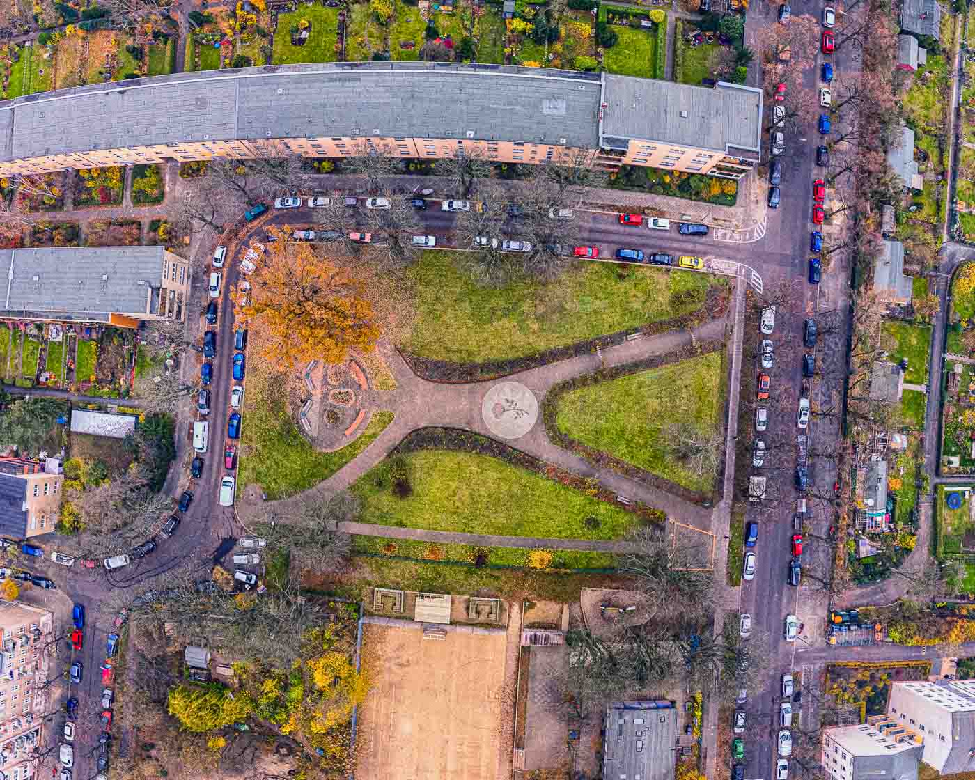 Berlin is a city full of surprises, and tucked away in the charming neighborhood of Neukölln-Britz lies one truly charming – Buschrosenplatz. This square might seem ordinary from the ground, but take to the skies, and you'll witness something truly magical.