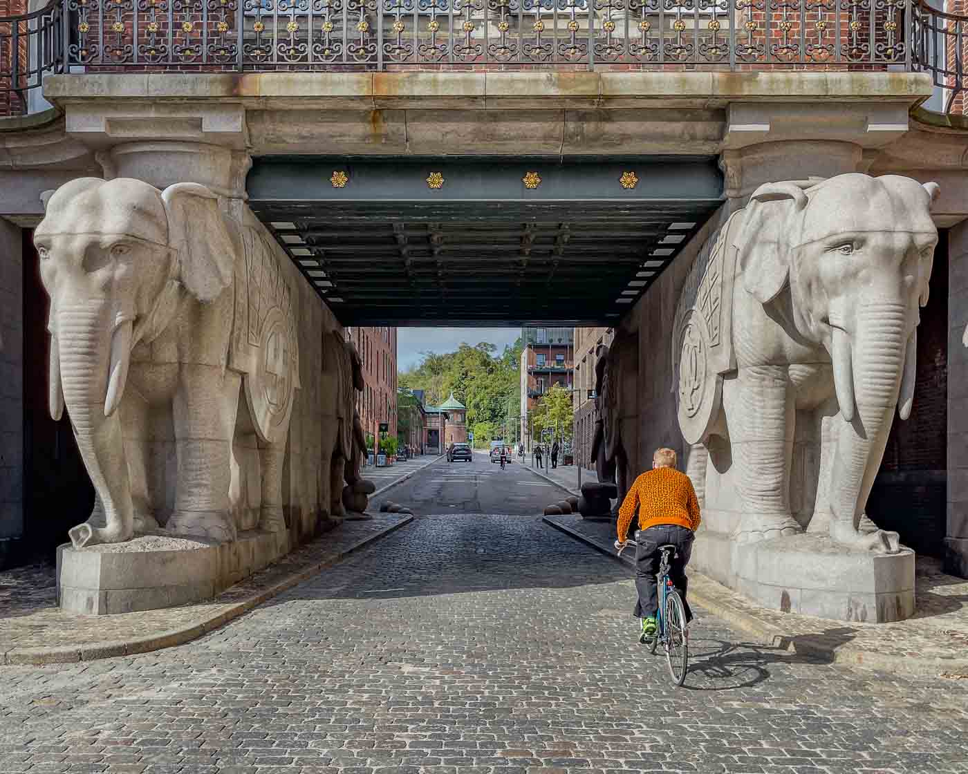 I went to visit the Elephant Gate at the old Carlsberg brewery site. This iconic landmark in town is a fascinating blend of history, architecture, and symbolism. The most notable feature is the four massive granite elephants that flank the gate, carrying the tower on their backs. And, if you pay attention to the pictures here, you might notice swastika symbols on the elephants’ blankets.