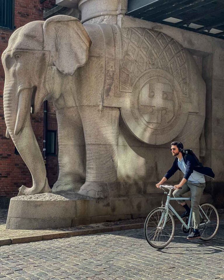 I went to visit the Elephant Gate at the old Carlsberg brewery site. This iconic landmark in town is a fascinating blend of history, architecture, and symbolism. The most notable feature is the four massive granite elephants that flank the gate, carrying the tower on their backs. And, if you pay attention to the pictures here, you might notice swastika symbols on the elephants’ blankets.