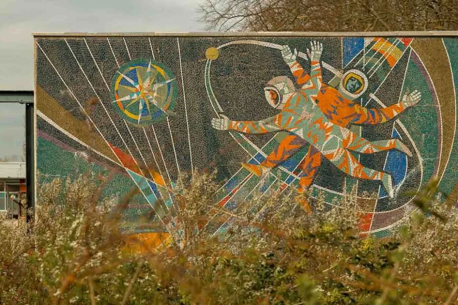 On one side, there is the Makrokosmos with two cosmonauts venturing into the vast expanse of space, reflecting the Soviet pride in the Space Race. On the other side, three scientists stand before symbols of atomic energy, illustrating the “promise” of nuclear power for a modern society.