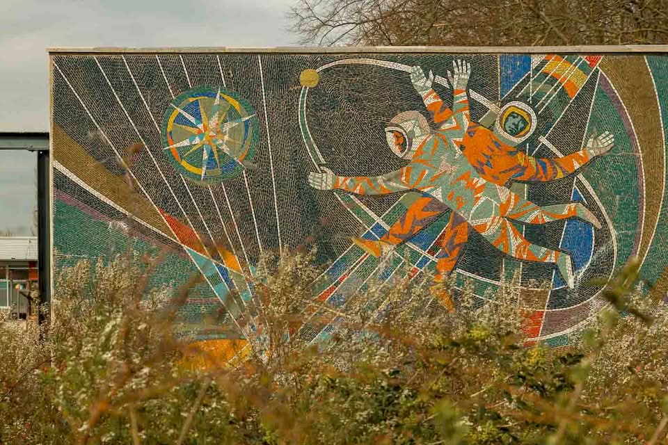On one side, there is the Makrokosmos with two cosmonauts venturing into the vast expanse of space, reflecting the Soviet pride in the Space Race. On the other side, three scientists stand before symbols of atomic energy, illustrating the “promise” of nuclear power for a modern society.