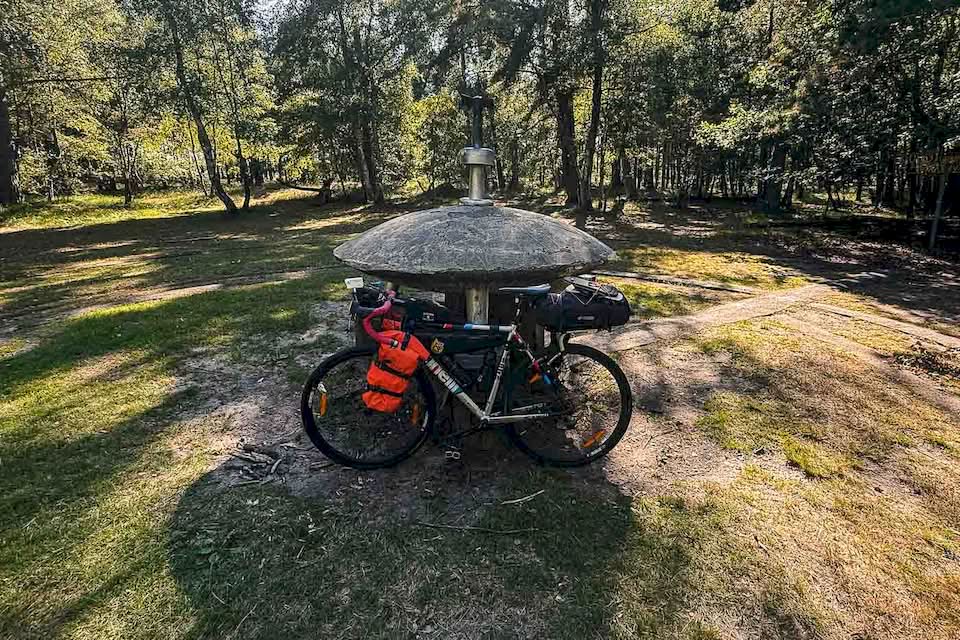 I think I rode for 90 km or so when my GPS tracker told me that the UFO memorial was close by. I stepped into the forest and tried to spot it. After a few wrong paths and turns, I saw a clearing in the woods, and there it was: a concrete model of a flying saucer in the middle of nowhere. I was in the right place.